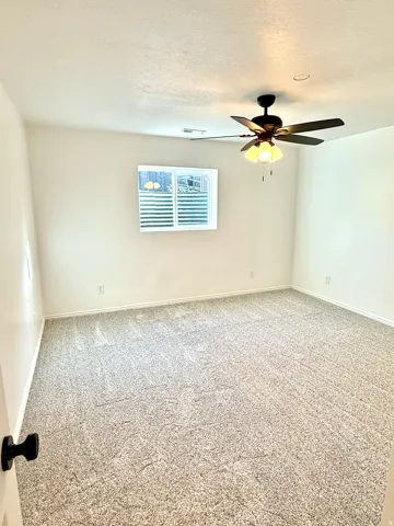 Neutral-toned wall-to-wall carpeting, white painted walls, and a ceiling-mounted fan light fixture