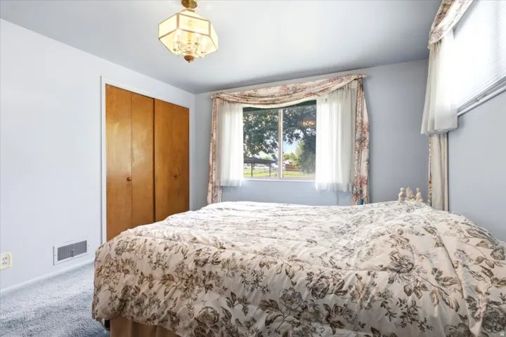 Recessed window with exterior views, dual-door closet with wood-finish doors, overhead lighting fixture, and light-toned wall finishes