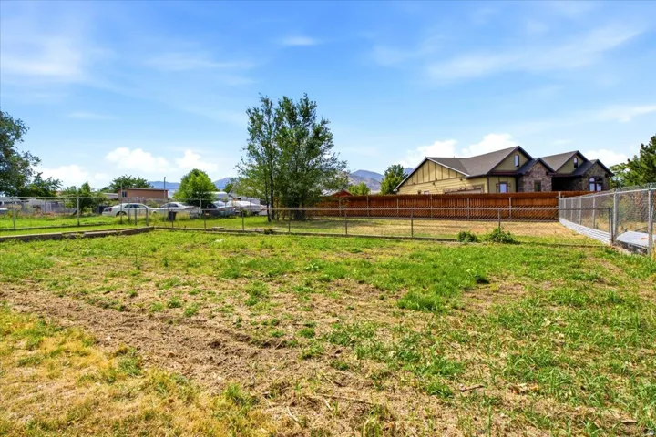 Expansive outdoor space featuring a chain-link fence and a wood privacy fence