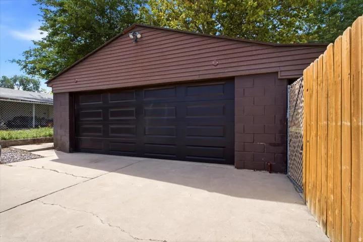 Two-car garage with a panel door, concrete block foundation, and horizontal siding