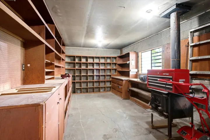Concrete flooring with extensive built-in wooden shelving, a large workbench area, and a utility window