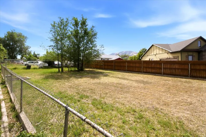 Expansive yard area featuring a chain-link perimeter fence and a solid wood privacy fence