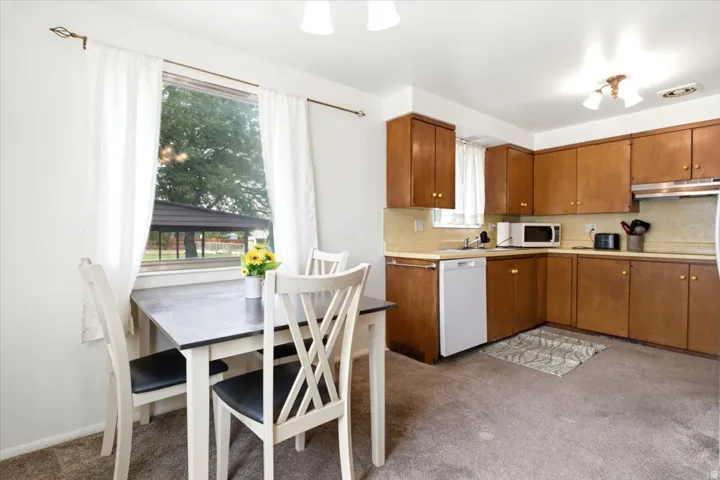 Kitchen featuring wood-finish cabinetry, light-toned countertops, and carpeted flooring