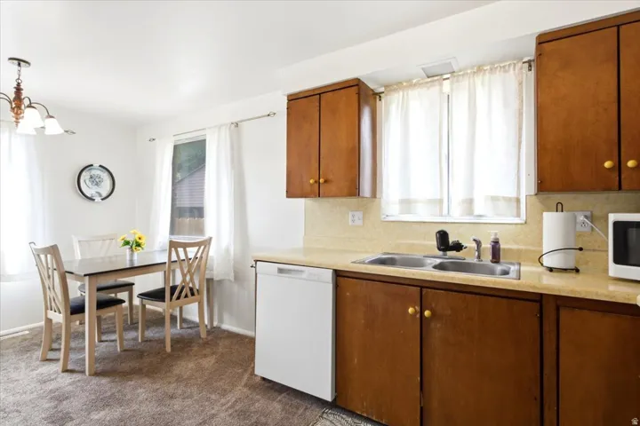 Kitchen featuring wood cabinetry, a double basin sink, and a white dishwasher