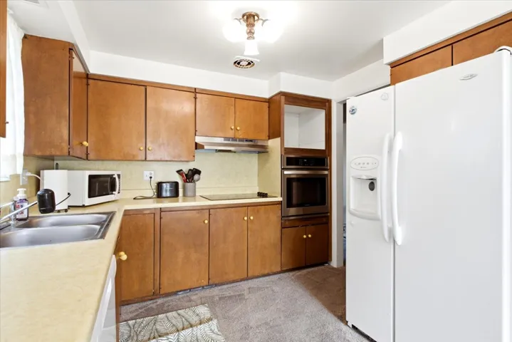 Kitchen featuring wood-finish cabinetry, built-in stainless steel oven, built-in microwave, and dual basin sink