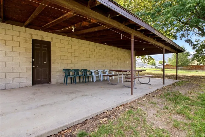 Covered patio area featuring a concrete slab, exposed wood beam ceiling, and a concrete block wall