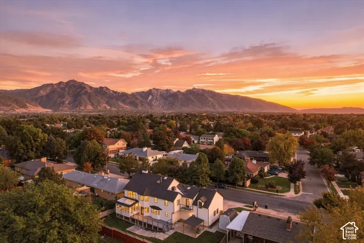 Aerial perspective showcasing the residential neighborhood with mature trees and mountain backdrop
