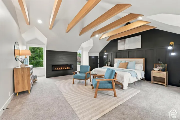 Vaulted ceilings with exposed wood beams, built-in linear fireplace, accent wall with paneling, and multiple windows