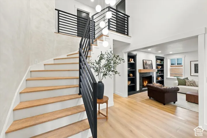 Two-story foyer with a curved staircase, wood-finish flooring, and a modern chandelier
