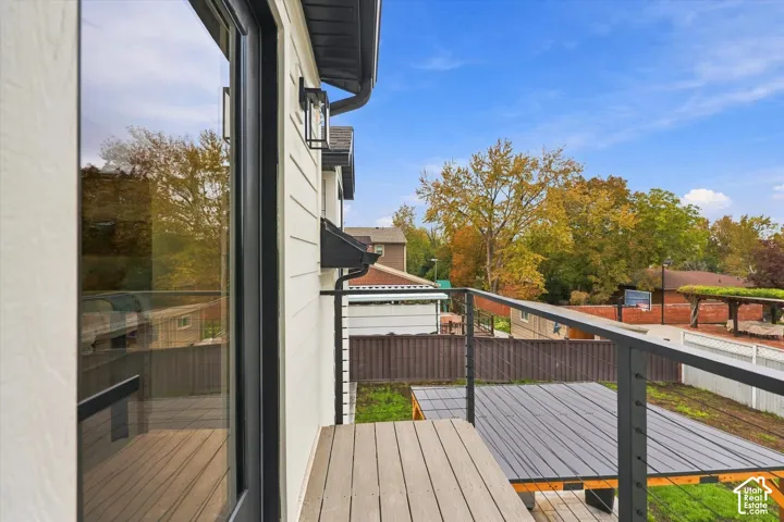 Private balcony with composite decking, black metal cable railing, and exterior wall lighting