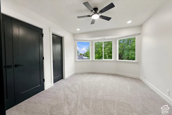 Bay window with multiple panes, ceiling fan with integrated lighting, recessed lighting, and dark panel doors with contemporary hardware