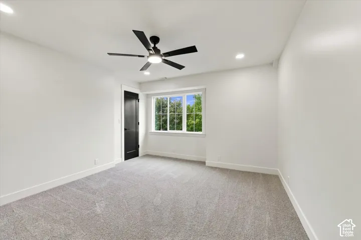 Recessed lighting, ceiling fan, dark-finish interior door, wall-to-wall carpeting, and a window with exterior scenery