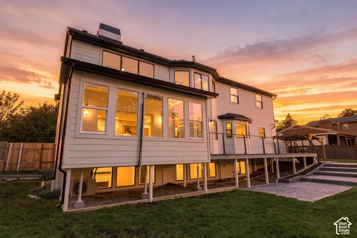 Two-story siding exterior with multiple windows, elevated deck with dark railings, paved patio, and tiered stone steps