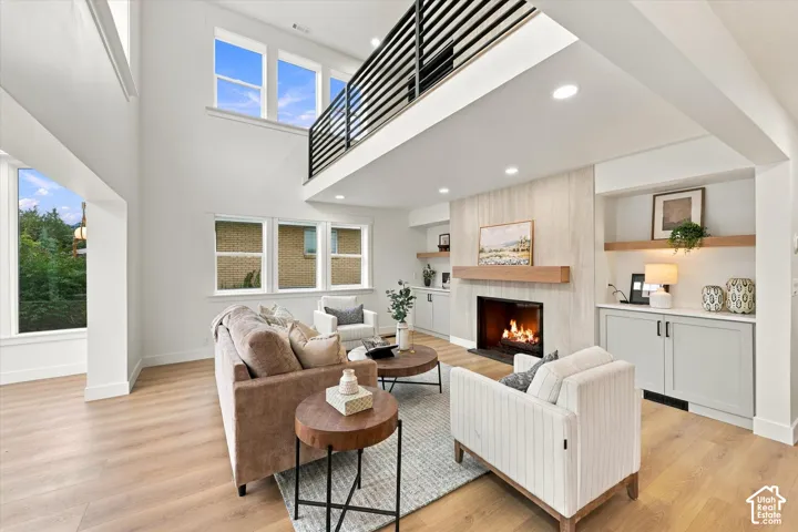 Vaulted ceilings, wood-finish flooring, and a fireplace with a wood mantle and stone surround