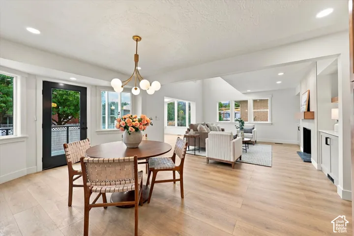 Wood-finish flooring throughout, modern chandelier, recessed lighting, white walls, and a built-in fireplace with a mantel