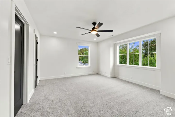 Spacious room featuring multiple windows, recessed lighting, a ceiling fan, and light gray carpeting