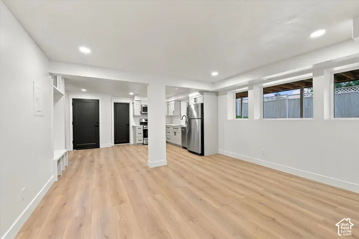 Open-concept living area with wood-finish flooring, recessed lighting, and multiple windows