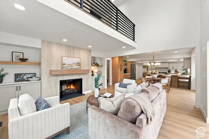 Vaulted ceiling, fireplace with wood mantel, built-in shelving, wood-finish flooring, and open-concept design