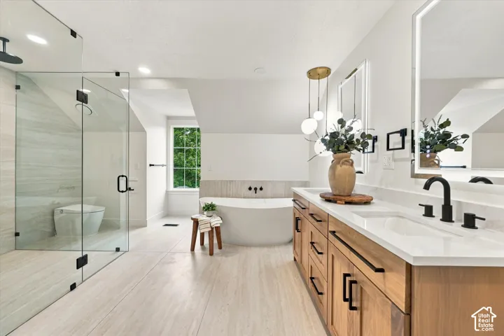 Modern bathroom featuring a glass-enclosed shower, freestanding soaking tub, wood-finish double vanity with white countertops, and illuminated mirrors
