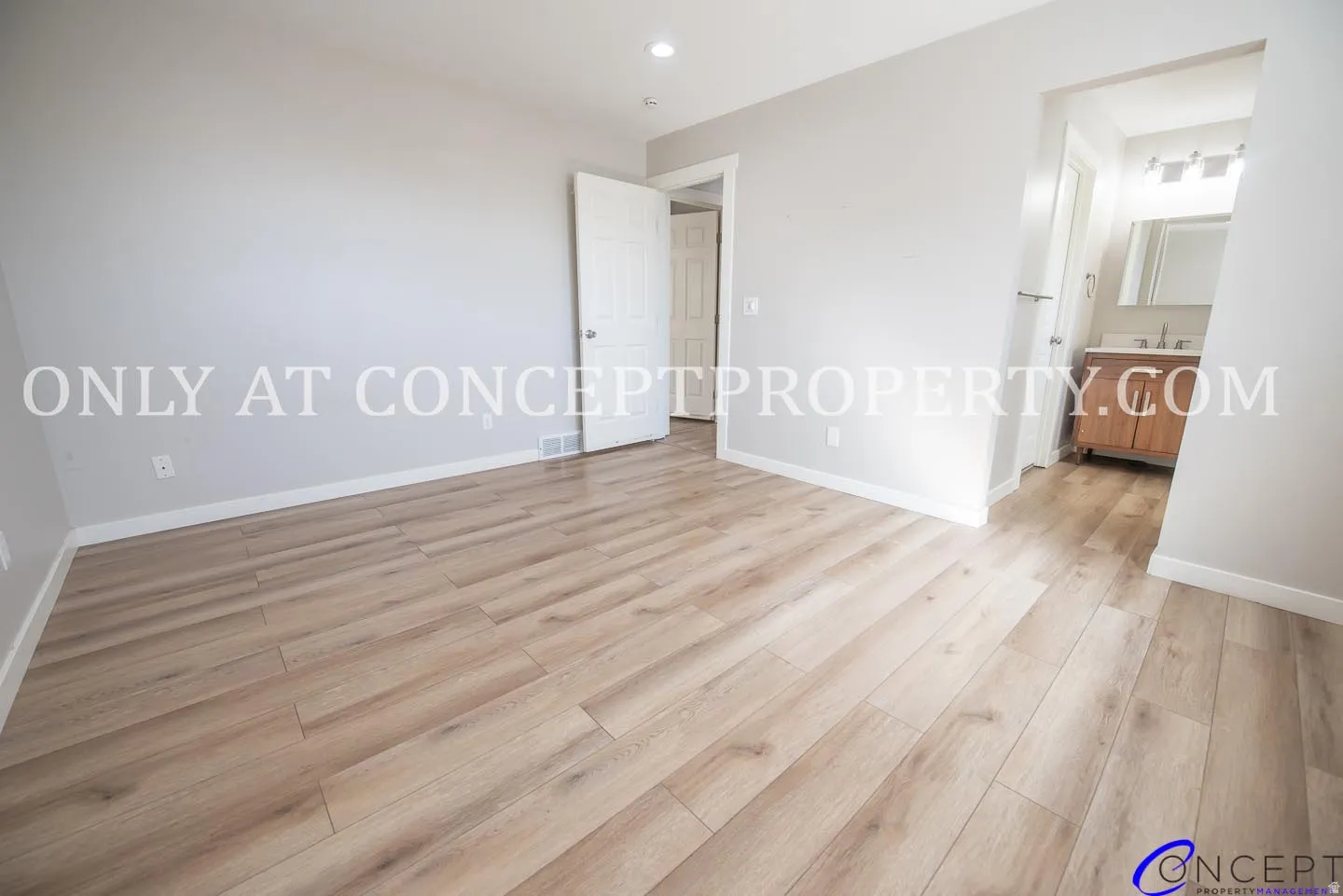 Wood-finish flooring throughout, light gray walls, and recessed lighting