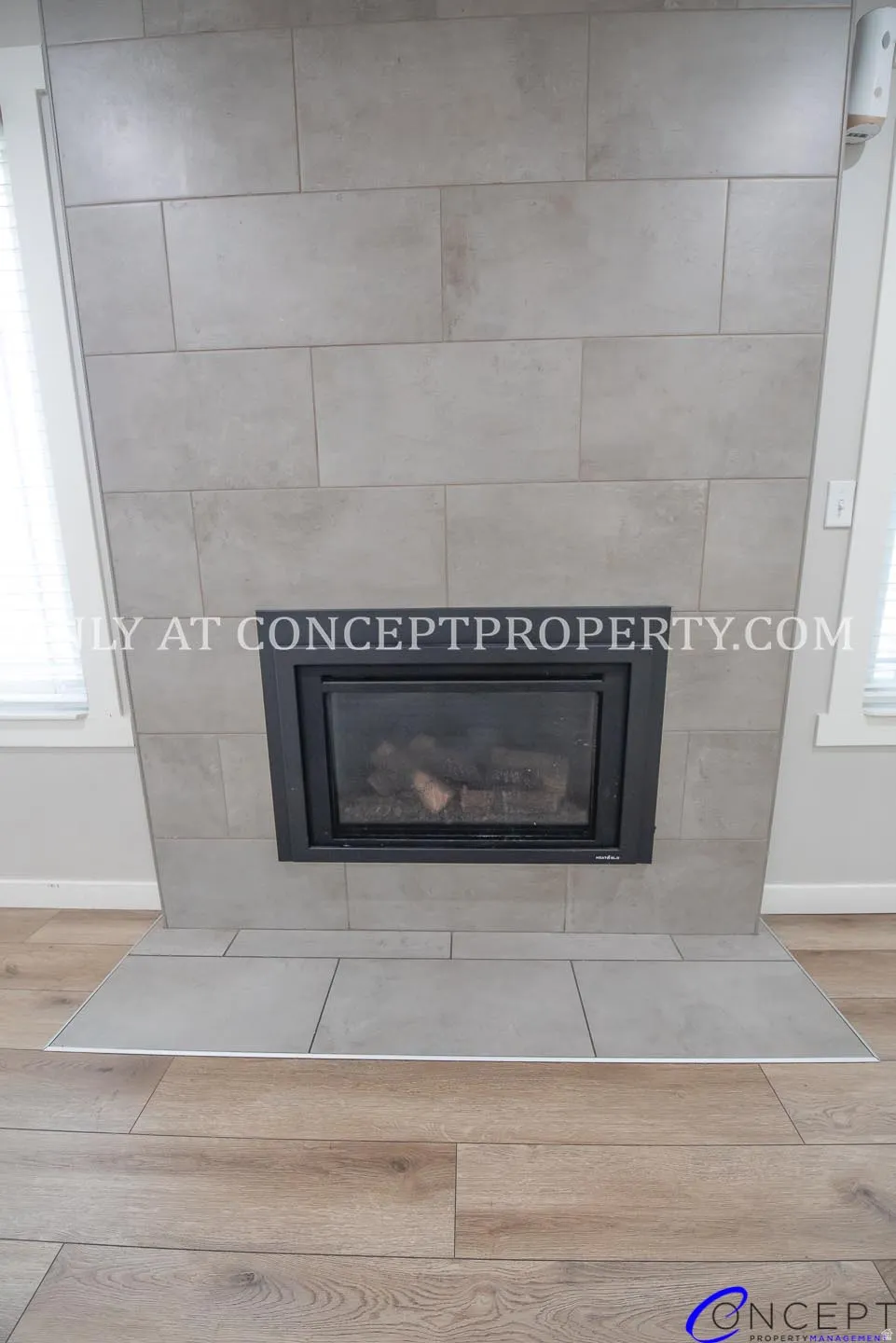 Integrated fireplace with a black surround, grey tile hearth, and complementary grey tile surround, set against wood-finish flooring
