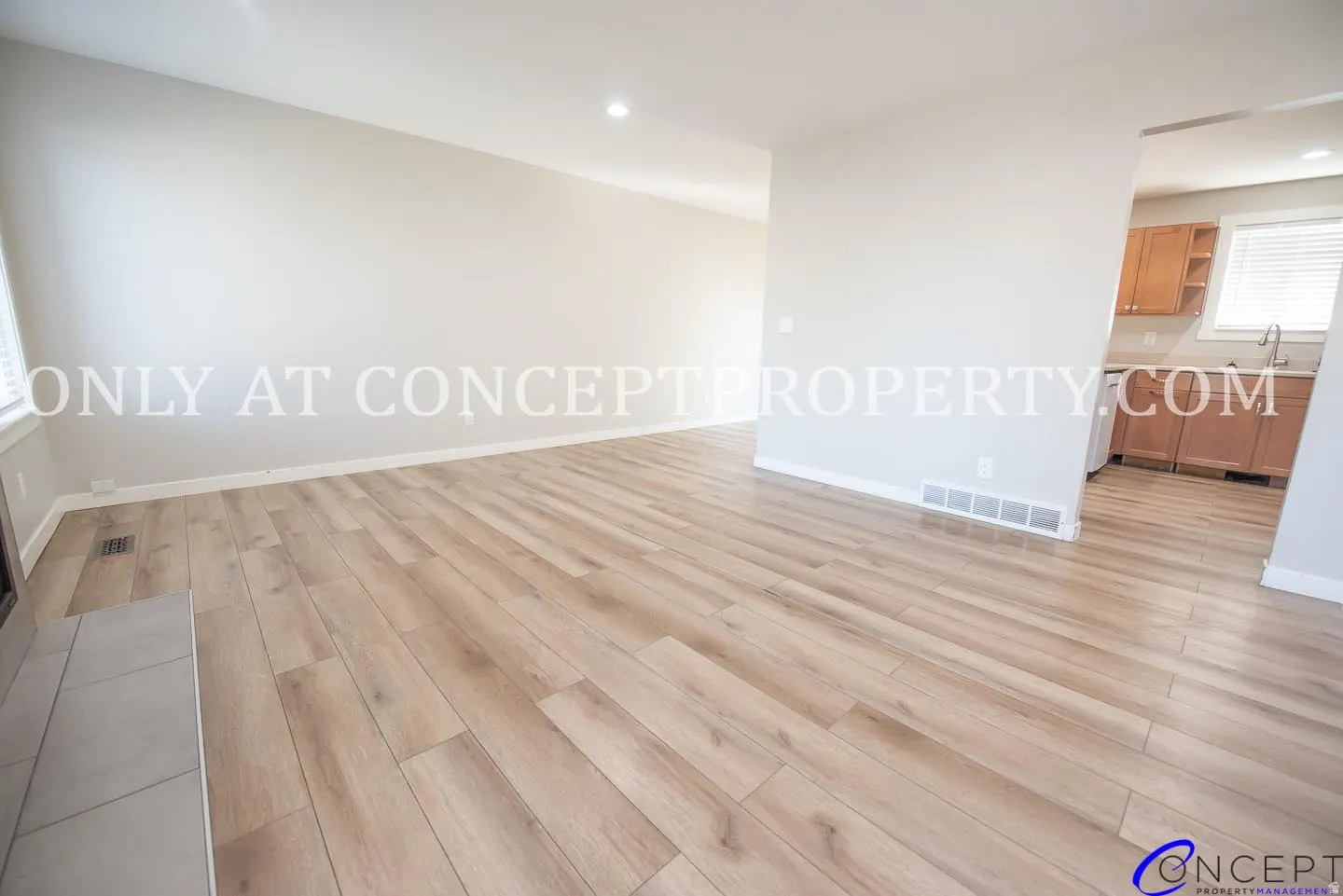 Wood-finish flooring throughout, light neutral wall tones, recessed lighting, and a window with blinds