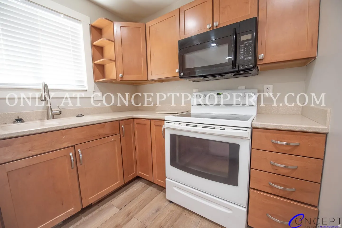 Light wood cabinetry, beige countertops, stainless steel sink with gooseneck faucet, white electric range, and wood-finish flooring