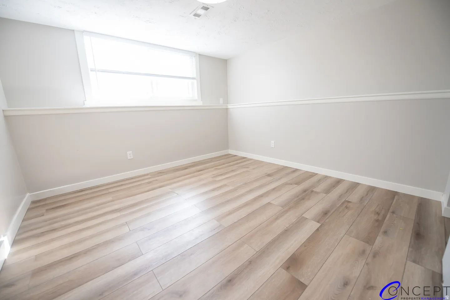 Wood-finish flooring with white trim, a single window, and neutral wall tones