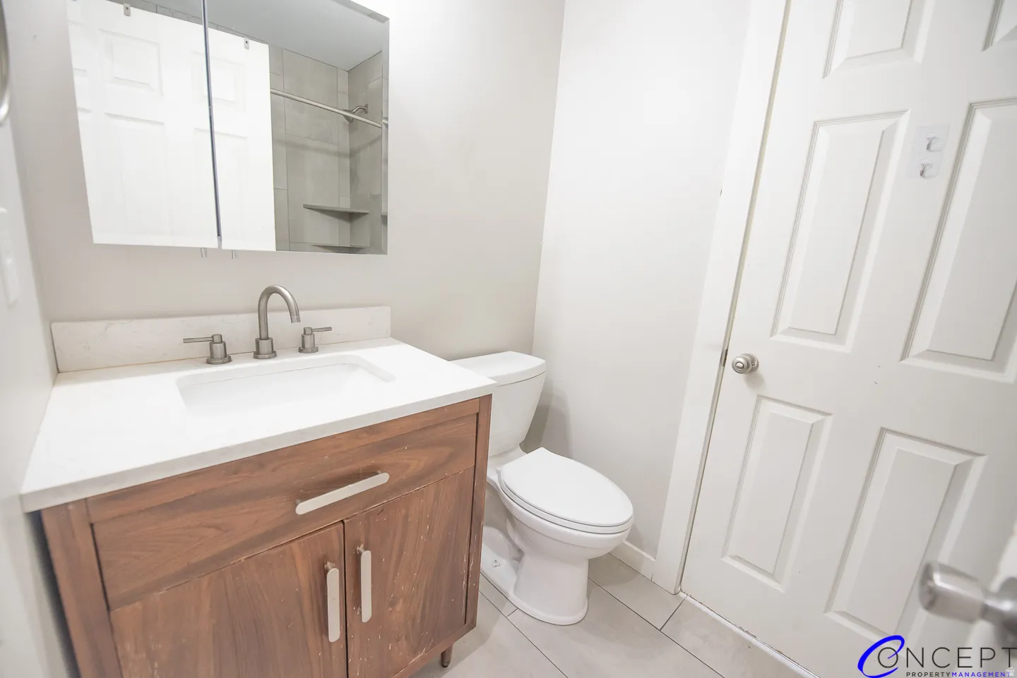 Wood-finish vanity with a white countertop, undermount sink, and brushed nickel fixtures