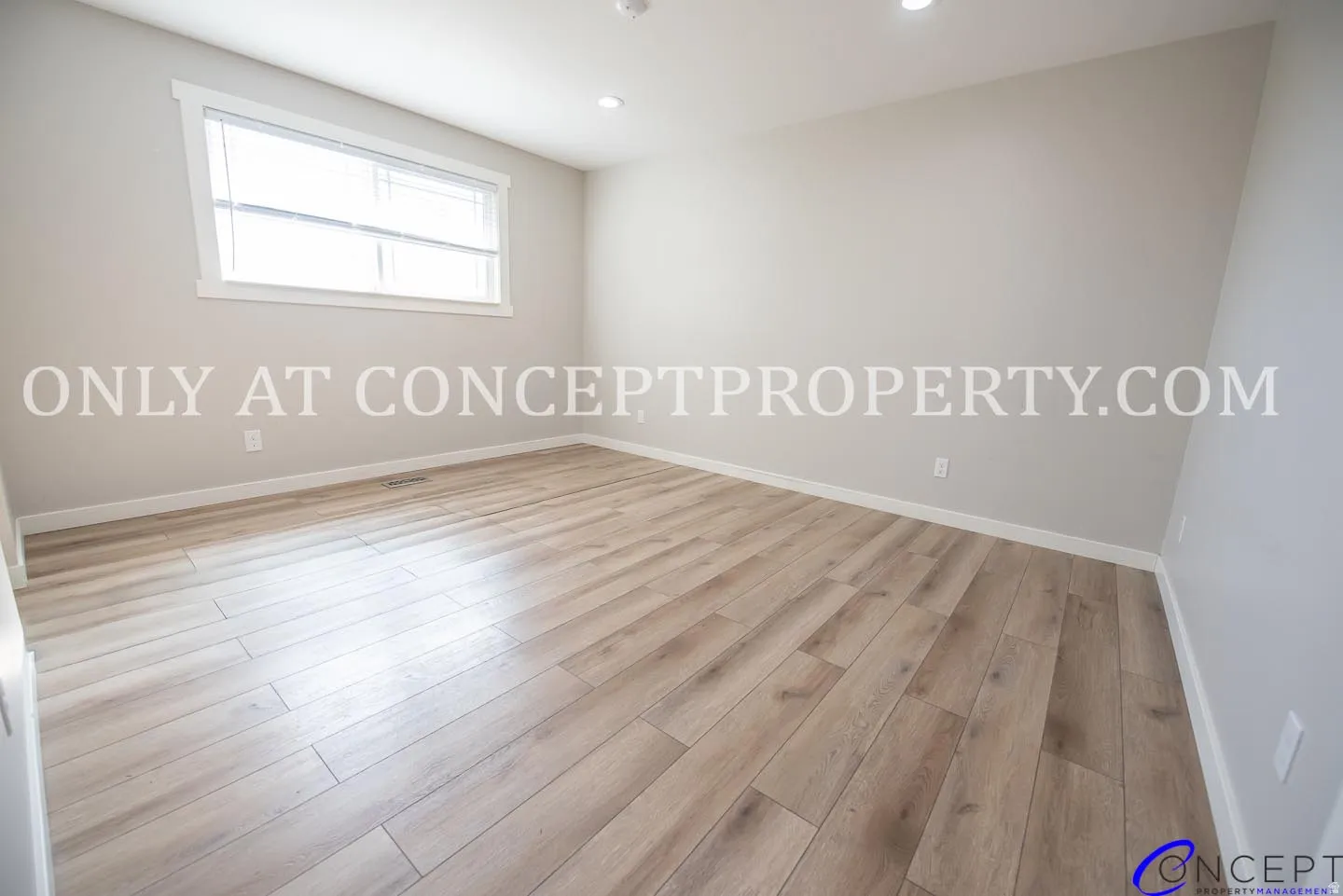 Light-toned wood-finish flooring, recessed lighting, and a white-trimmed window