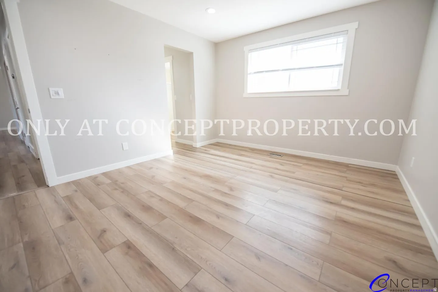Light-toned wood-finish flooring, recessed lighting, and a window with white trim