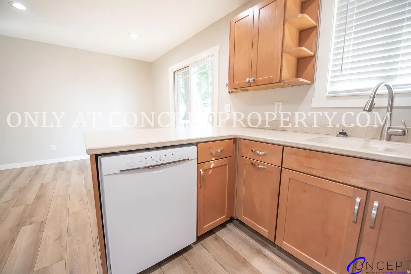 Kitchen featuring wood-finish cabinetry, light countertops, and an integrated dishwasher