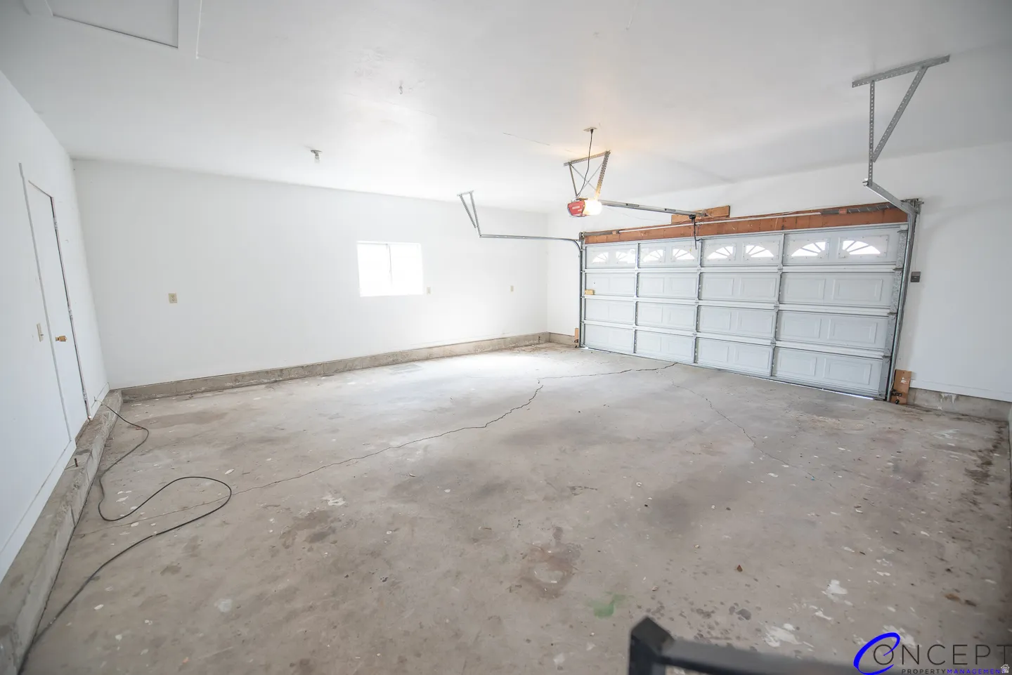 Attached garage with a sectional overhead door, a single window, and a painted interior