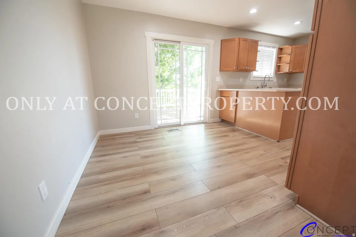 Wood-finish flooring, sliding glass door, light wood cabinetry, recessed lighting, and a kitchen island