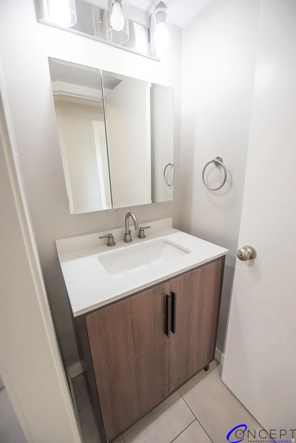 Vanity with wood-finish cabinetry, integrated sink, and white countertop