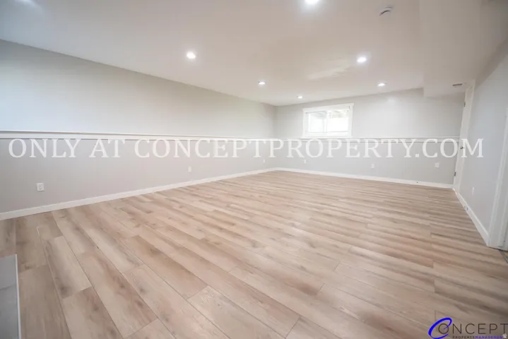 Recessed ceiling lighting, wood-finish flooring, white walls, white trim, and a window