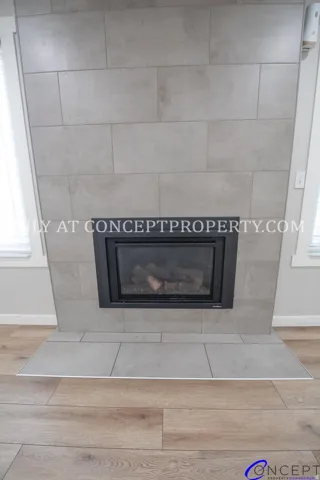 Integrated fireplace with a black surround, grey tile hearth, and complementary grey tile surround, set against wood-finish flooring