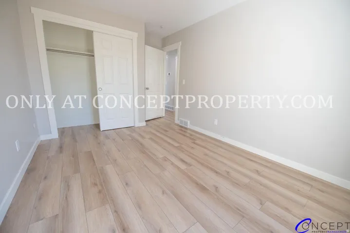 Wood-finish flooring, light grey wall paint, white trim, sliding closet doors, and recessed closet space