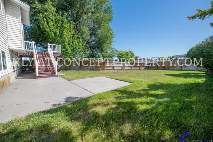 Expansive backyard featuring a manicured lawn, established privacy fencing, and a concrete patio
