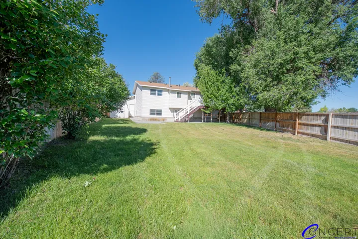 Expansive green lawn with mature trees and wood fencing