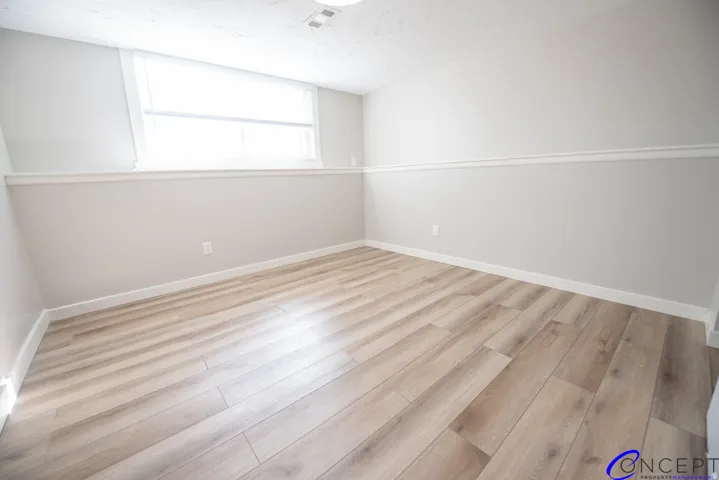 Wood-finish flooring with white trim, a single window, and neutral wall tones