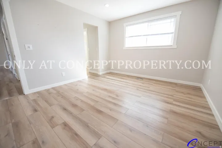 Light-toned wood-finish flooring, recessed lighting, and a window with white trim