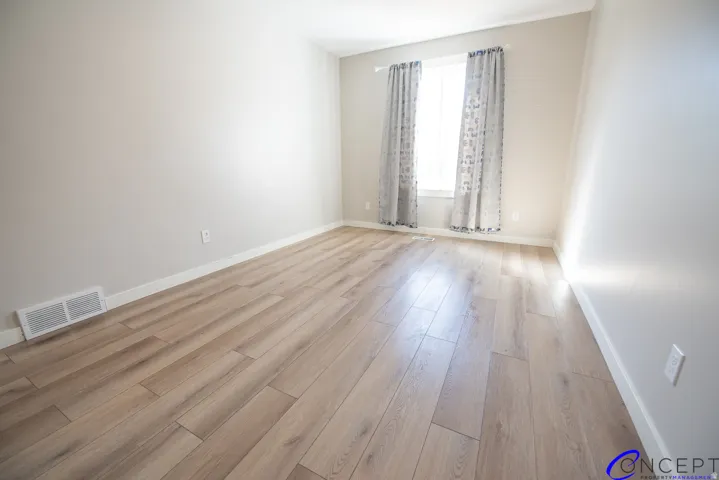 Wood-finish flooring, neutral wall tones, white trim, and a window with natural light