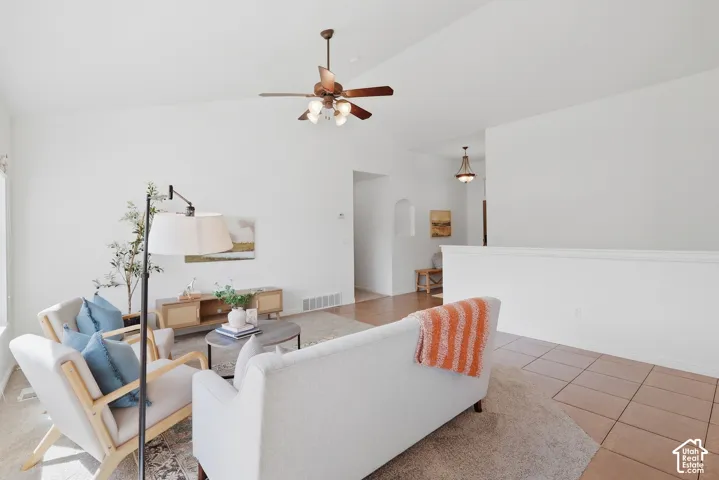 Vaulted ceilings, a ceiling fan with integrated lighting, wood-finish flooring, and a tiled entry