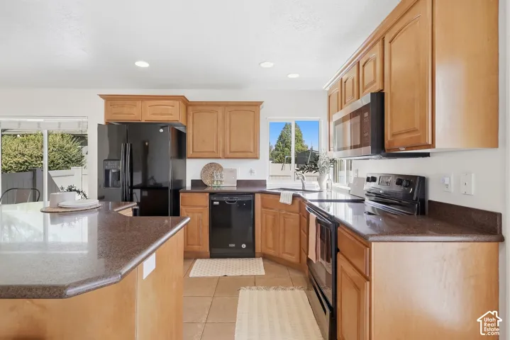 Kitchen featuring wood cabinetry, stone-look countertops, and black built-in appliances