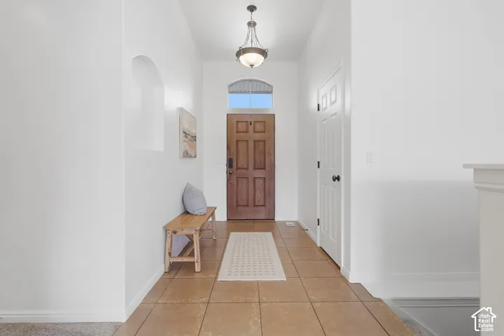 Entryway featuring tile flooring, a paneled wood entry door with an arched transom, a built-in wall niche, and an overhead pendant light fixture
