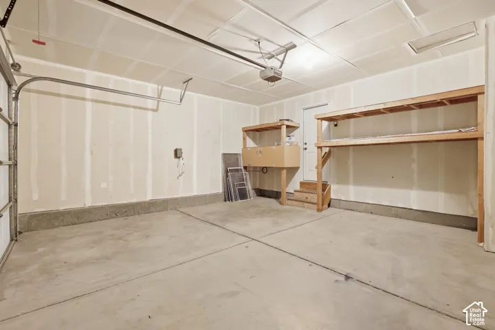 Concrete flooring, overhead garage door system, built-in wooden shelving, service door