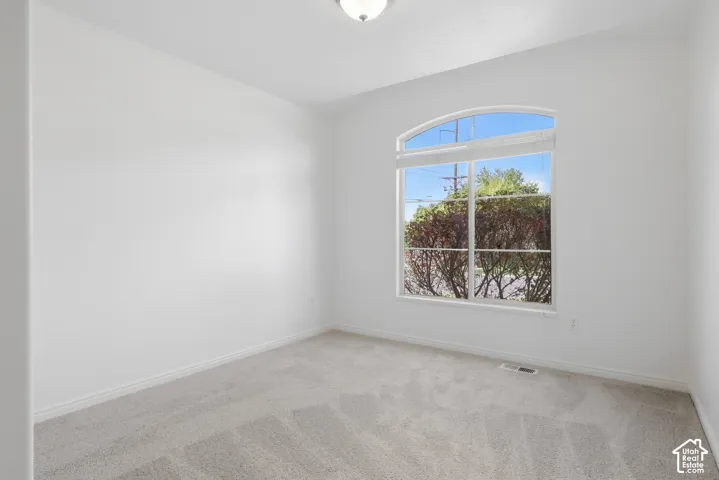 Arched window, recessed light fixture, carpeted flooring, and neutral wall finishes