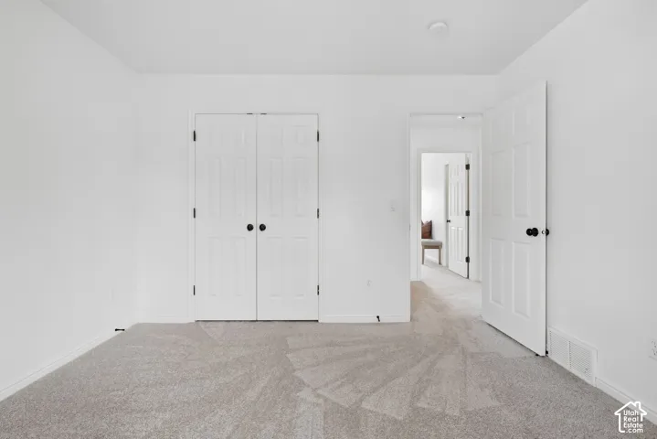 Light gray carpeted flooring, white paneled doors with black hardware, and crisp white walls