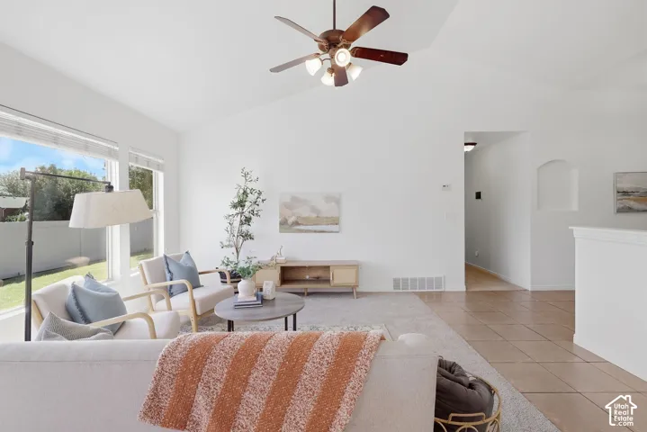 Vaulted ceilings with a ceiling fan, expansive windows, recessed wall niche, and tile flooring